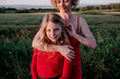 © Oxana Guryanova/Westend61 - Mother stroking daughte's hair, standing in a poppy field
