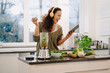 © Westend61 - Fit woman standing in kitchen, preparing healthy smoothie, using online recipe
