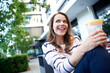 © philipp nemenz/Westend61 - Smiling woman having a break in the city holding a cup