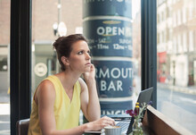 Thoughtful Young Businesswoman With Laptop At Coffee Shop