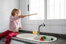 Little Girl Fishing Rubber Ducks In  Kitchen Sink