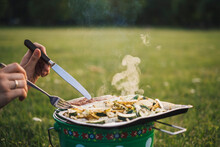 Woman Eating Barbecued Sausages And Vegetables On A Meadow, Partial View