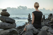 © Petra Stockhausen/Westend61 - Spain, Tenerife, Costa Adeje, woman sitting between cairns at the coast