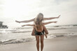 © LOUIS CHRISTIAN/Westend61 - Young woman piggybacking female friend at beach against clear sky