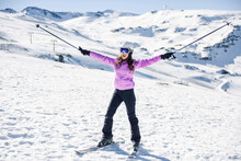 Happy Woman Raising Her Ski Poles In Snow-covered Landscape In Sierra Nevada, Andalusia, Spain