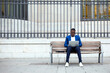 © Lifestock/Westend61 - Young businessman wearing blue suit jacket sitting on bench and using laptop