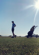 Teenage boy standing by golf bag on land against clear sky during sunny day