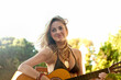 © LOUIS CHRISTIAN/Westend61 - Smiling young woman playing guitar in bikini at beach