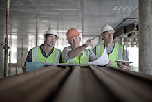 Male Construction Worker Discussing Plan With Coworkers At Construction Site