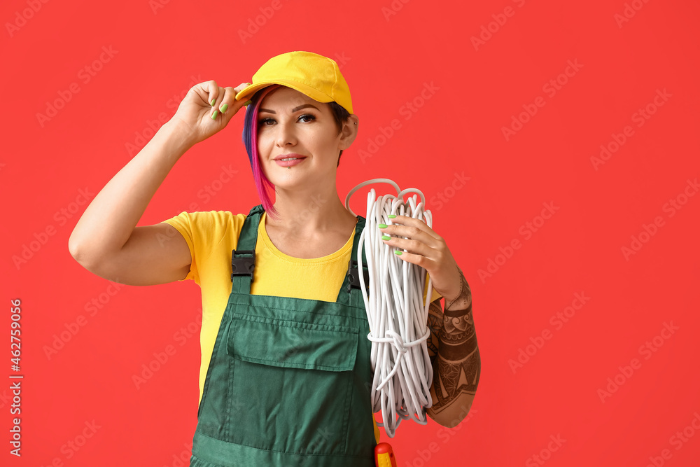 Female electrician with cables on color background