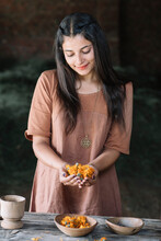 Beautiful Woman Looking At Orange Flowers On Clasped Hands
