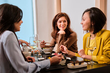Smiling Female Customers With Chopsticks Having Sushi At Restaurant