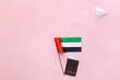 National United Arab Emirates flag, passport and paper plane on pink background