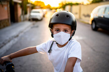 Boy Wearing Protective Face Mask And Helmet On Bicycle During Sunset