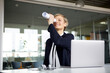 © Rainer Berg/Westend61 - Smiling businesswoman looking through paper roll at desk in office