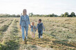 © Westend61 - Smiling mother with two children walking on field
