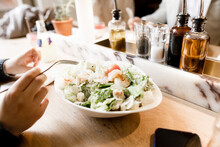 Teenage Boy Eating A Cersar's Salad With Prawns In A Restaurant