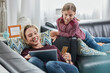 © Roger Richter/Westend61 - Happy mother and daughter shopping online on couch at home