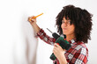 © Retales Botijero/Westend61 - Woman using portable drill, marking with pencil on a wall