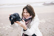 © Katharina Mikhrin/Westend61 - Portrait of relaxed woman taking photos on the beach with camera