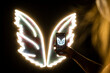 © Westend61 - Arm of young woman taking smart phone photo of white glowing neon wings