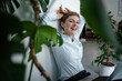© KNSY/Westend61 - Portrait of a businesswoman with laptop sitting on the floor surrounded by plants