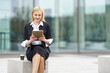 © GER/Westend61 - Blond businesswoman using digital tablet while sitting on bench against building