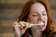 © KNSY/Westend61 - Portrait of redheaded woman brushing teeth