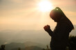 © Tinnakorn - woman praying in the morning concept of christianity rising sun background Concept of prayer, faith, hope, love, liberation.