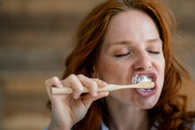 Portrait Of Redheaded Woman Brushing Teeth