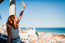 Young Woman Sitting And Gesturing Peace Sign At Alfama, Lisbon, Portugal