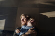 © KNSY/Westend61 - Happy father and son cuddling on the floor at home