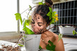 © GERMAN GONZALEZ/Westend61 - Woman covered with plant leaf smelling potted plant mud at home