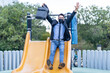 © GERMAN GONZALEZ/Westend61 - Carefree businessman wearing face mask playing on slide at park during Covid-19