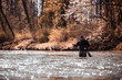 Fly Fisherman casting fishing line while standing in river at forest