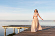 © Westend61 - Full length of smiling beautiful woman walking on pier over lake against sky