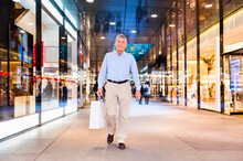 Portrait Of Happy Senior Man With Shopping Bag In A Shopping Center