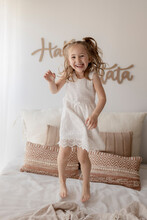 Portrait Of Happy Little Girl Jumping On Bed