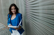 © Gala Mart√≠nez L√≥pez/Westend61 - Female entrepreneur reading file document while standing against wall
