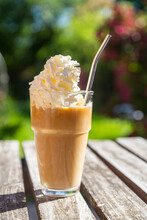 Glass Of Iced Coffee With Cream Topping On Garden Table