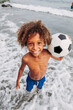 © DREAMSTOCK1982/Westend61 - Portrait of a smiling boy holding a football on the beach