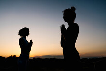 Silhouette Of Women In Prayer Position Outdoors