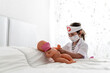 © ezequiel gimenez appelhans/Westend61 - Girl in doctor's costume caring of her doll with a mask