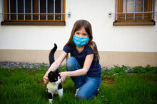 Girl Wearing Protective Mask And Stroking Her Cat In Garden