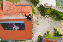 Aerial View Of Chimney Sweep Working On House Roof