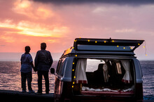 Senior Couple Traveling In A Vintage Van, Watching Sunset At The Sea