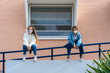 © Westend61 - Teenage friends social distancing while wearing protective face mask sitting on railing during covid-19