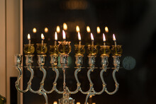 Hanukkah Candles Are Lit In A Silver-decorated Menorah, Against A Black Background Of The Night - The Jewish Holiday Of Hanukkah