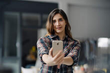 Portrait Of Smiling Young Woman Taking Selfie In A Loft