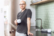 © Maya Claussen/Westend61 - Man with a cup standing in the morning at home in the kitchen